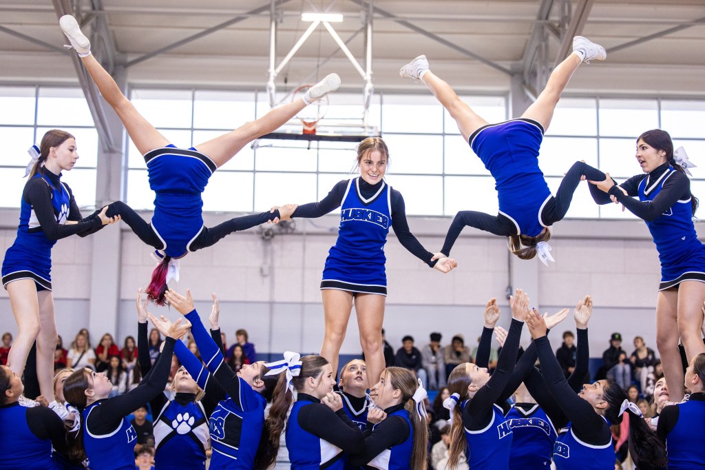 A group of cheerleaders performing a stunt, with one cheerleader balanced on top while others support her from below during a performance.